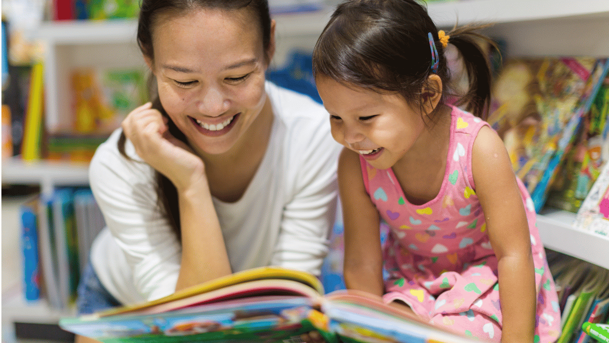 Adult and child sharing a book during a classroom activity